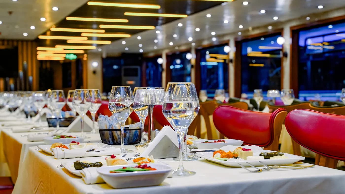 Mesa elegantemente posta com copos de vinho na sala de jantar do barco à noite