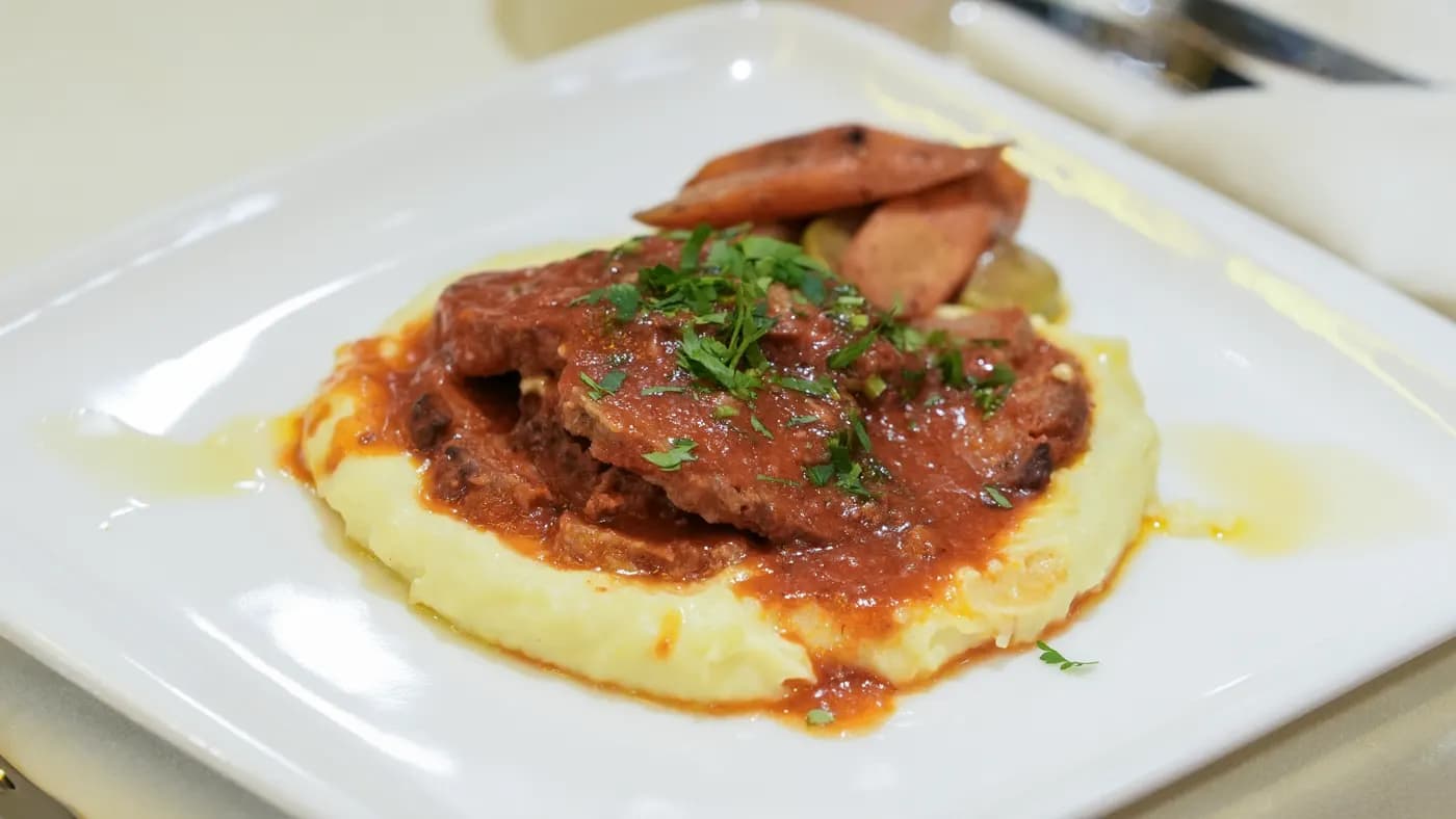 Prato principal de vaca grelhada servido com puré de batata e legumes assados