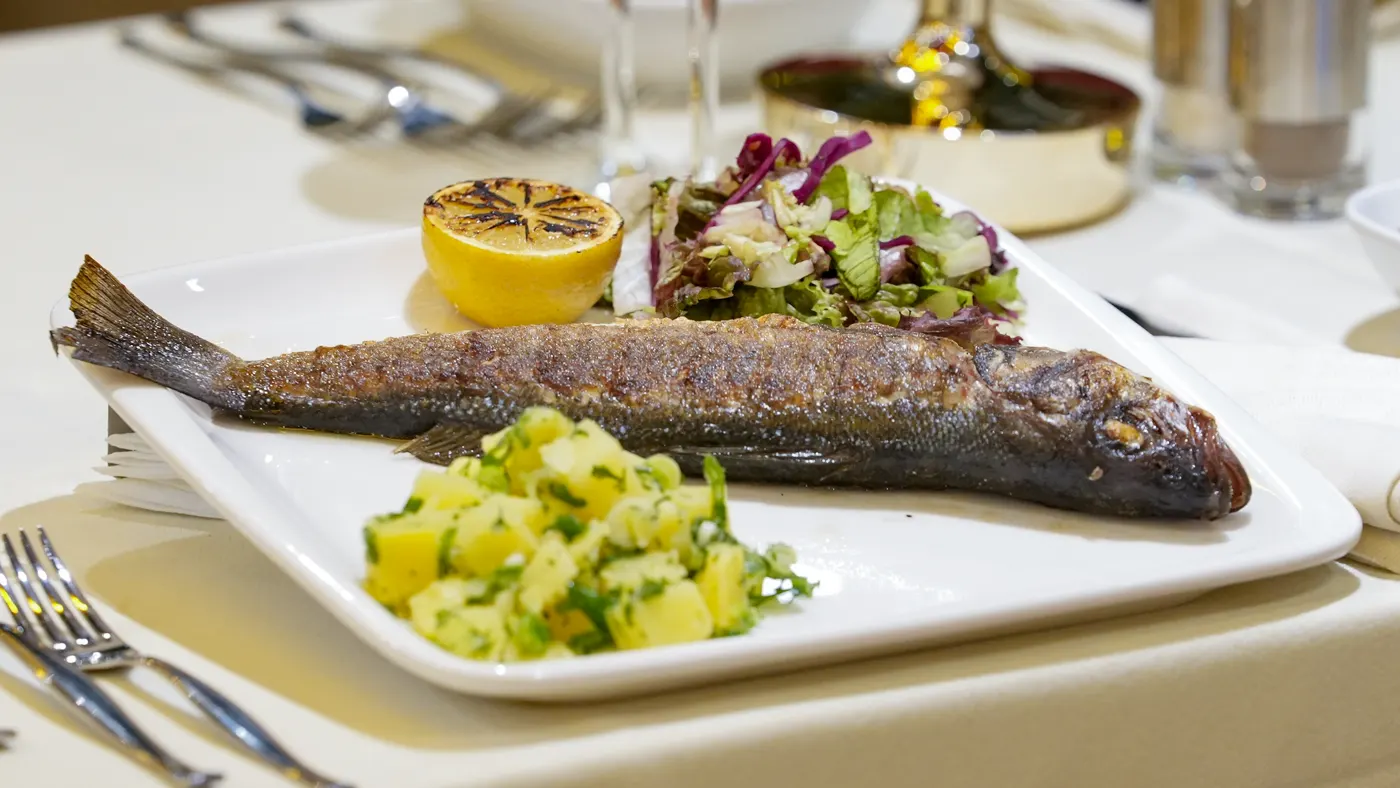 Whole grilled sea bass served with potato salad and grilled lemon