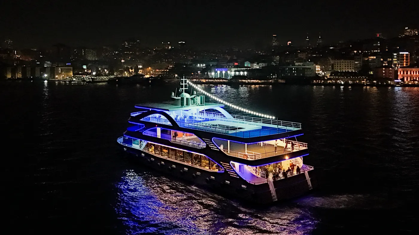 Touronic Cruise ship sailing the Bosphorus at night with Istanbul skyline behind it